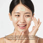 Woman applying a facial mask with text about skincare benefits on a white background